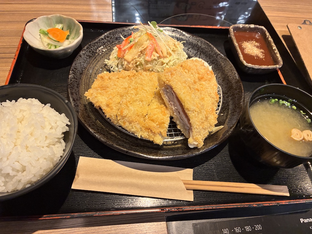 Crispy Japanese tonkatsu pork cutlet set meal with rice, miso soup, pickles, and salad at Airport Shokudo Naha
