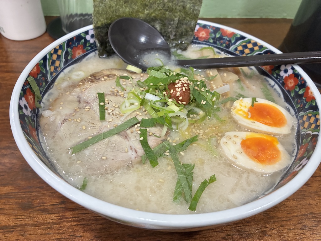 Rich tonkotsu pork bone ramen with chashu pork, soft-boiled egg, scallions, and nori at a Naha Airport ramen counter