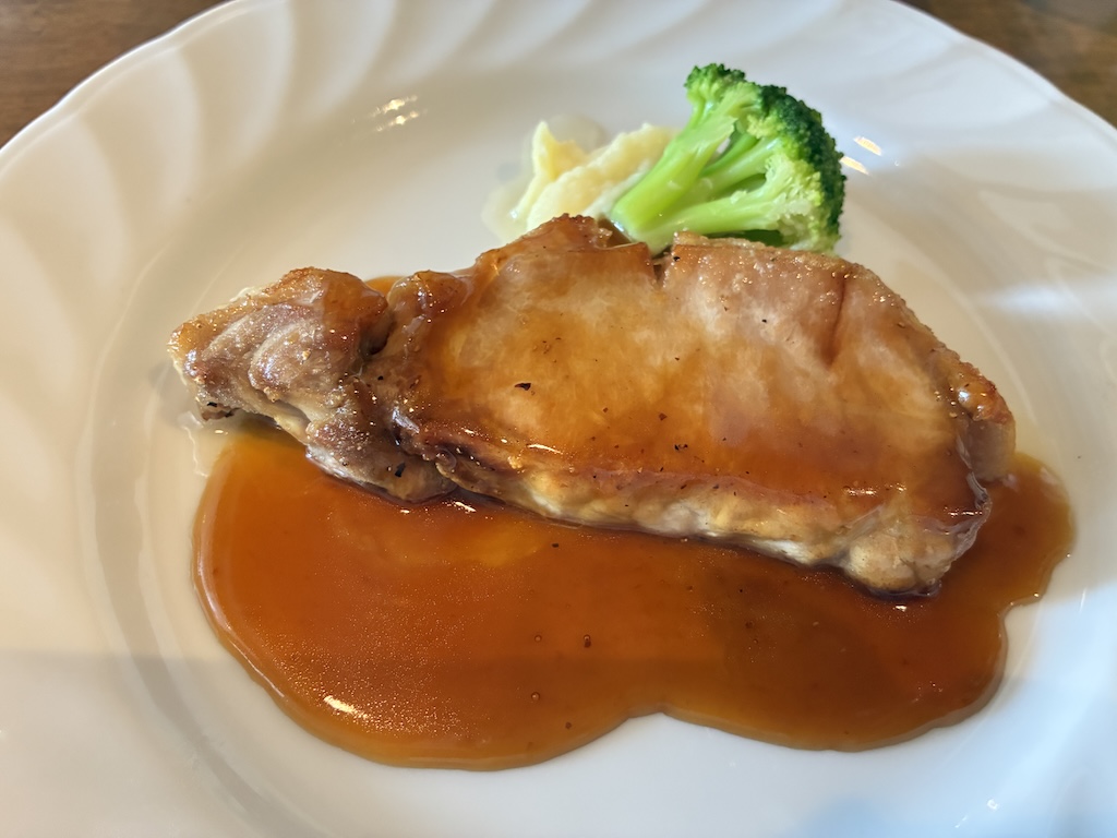 Western-style chicken or pork chop in glossy demi-glace sauce with steamed broccoli at a Naha Airport restaurant