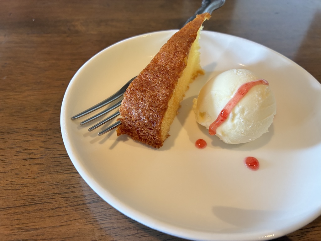 Slice of golden butter pound cake with vanilla ice cream and raspberry sauce — light dessert at a Naha Airport cafe before flying home