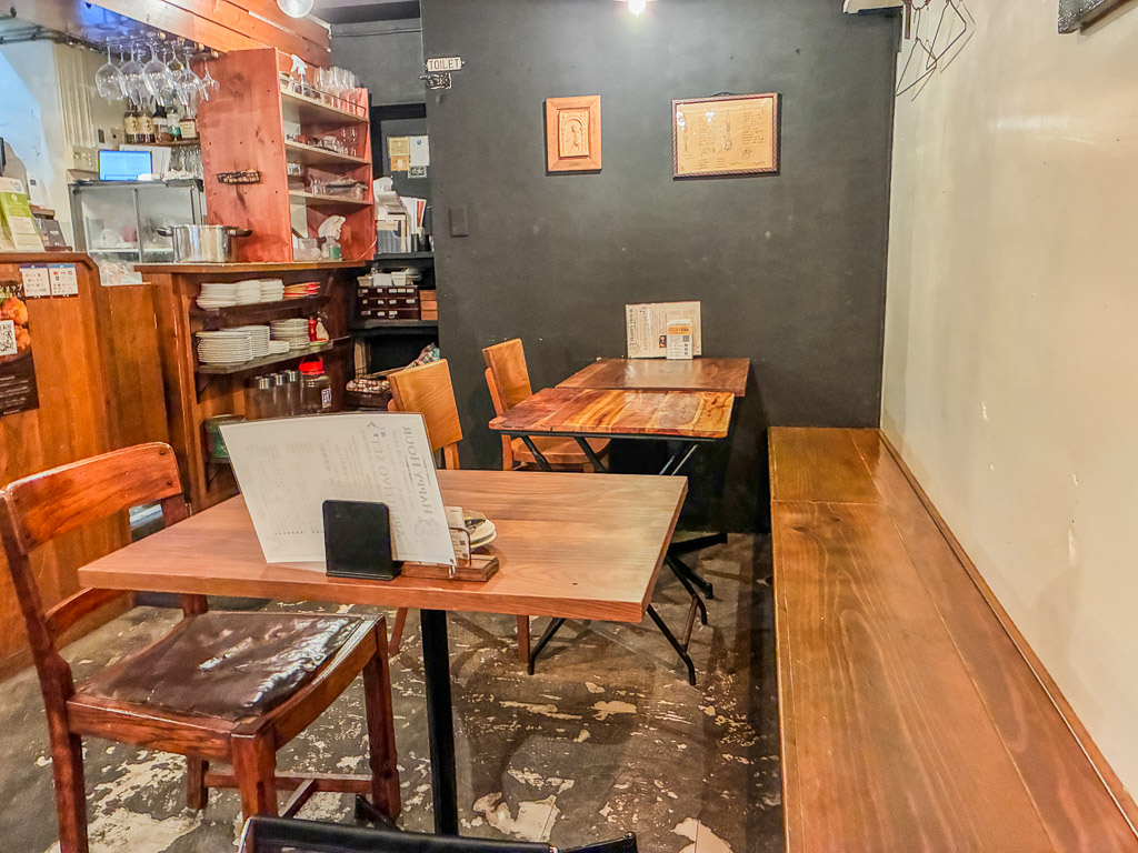 ALGOS DELI×HAMBURG dining area — wooden tables and chairs with framed menu prints on the wall