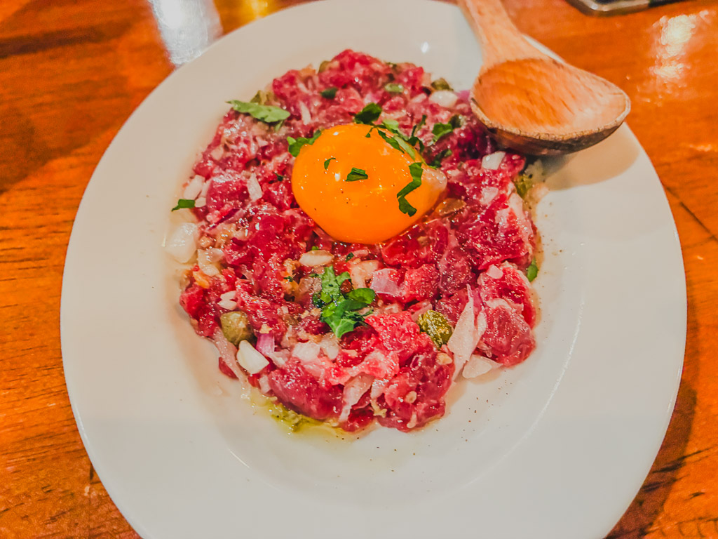 ALGOS DELI×HAMBURG beef tartare — finely chopped raw beef topped with an egg yolk, capers, and minced onion