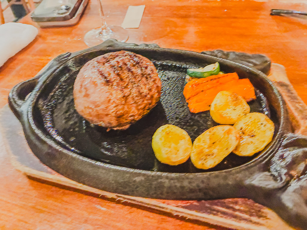 ALGOS DELI×HAMBURG Kuroge wagyu hamburg steak — thick patty on a cast-iron skillet with grilled vegetables