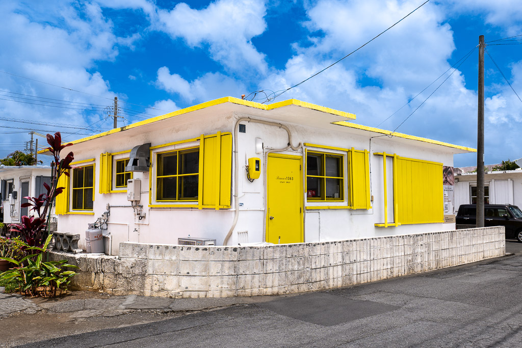 港川 (Minatogawa) bright yellow solid-color facade with shutters — Okinawa Urasoe American Stateside town color stroll photo spot