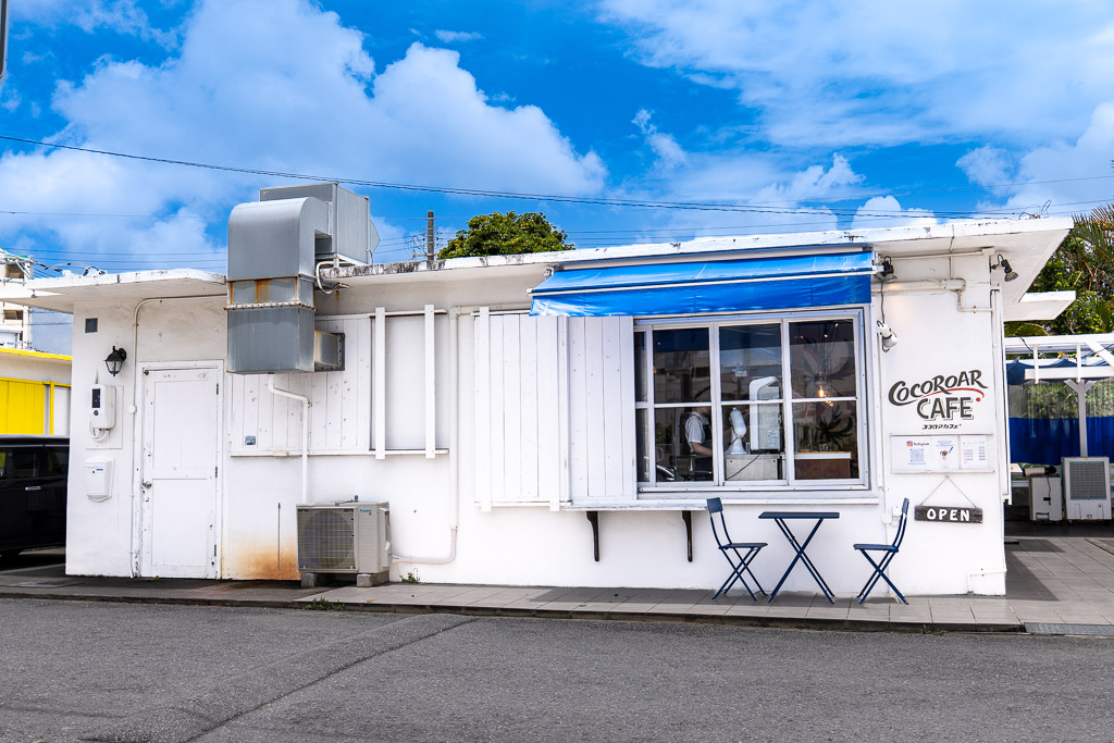 港川 (Minatogawa) COCOROAR CAFE white exterior with blue awning — Okinawa Urasoe cafe inside Stateside housing