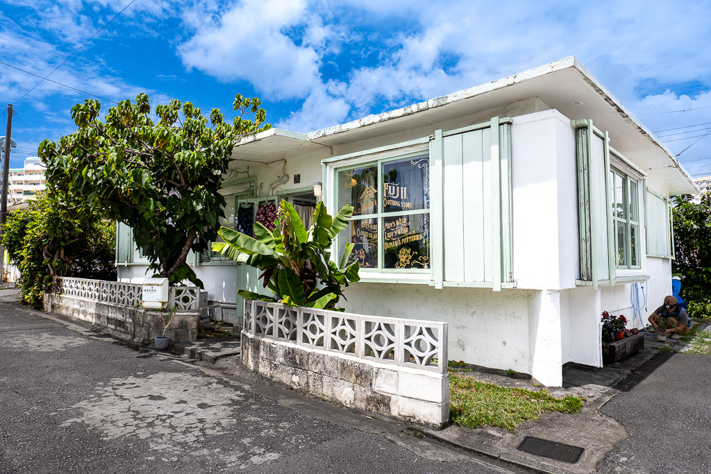 港川 (Minatogawa) FUJI clothing store white with mint shutter and lush plant garden — Okinawa Urasoe clothing boutique