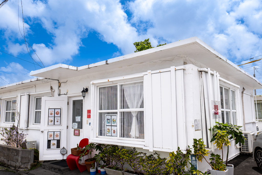 港川 (Minatogawa) modern white exterior with red chairs, cafe and goods tone — Okinawa Urasoe
