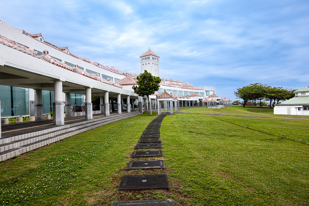 Side view of museum colonnade with Peace Memorial Hall tower in the distance — grass garden