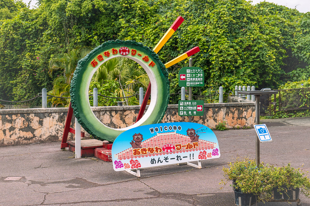 Entrance of Okinawa World with ICO mascot and colourful sign — Mensōrē welcome board