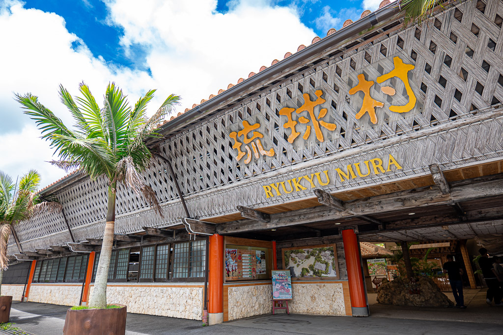 Ryukyu Village main entrance with massive woven-style roof and yellow RYUKYU MURA signboard
