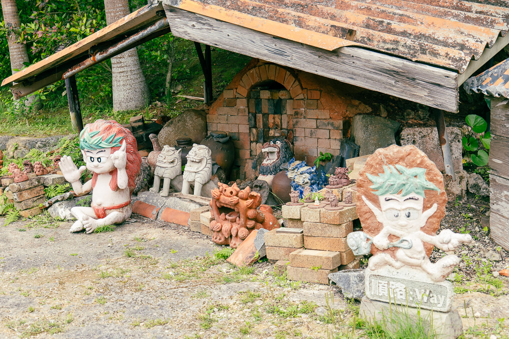 Shisa pottery kiln with colorful Shisa figurines displayed in front of red brick kiln and Okinawan sculptures