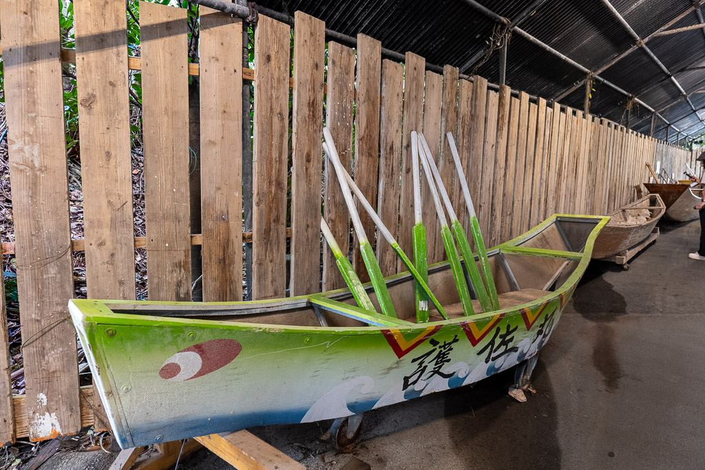 Traditional Ryukyuan Sabani fishing boat — green wooden boat and oars displayed under wooden shelter