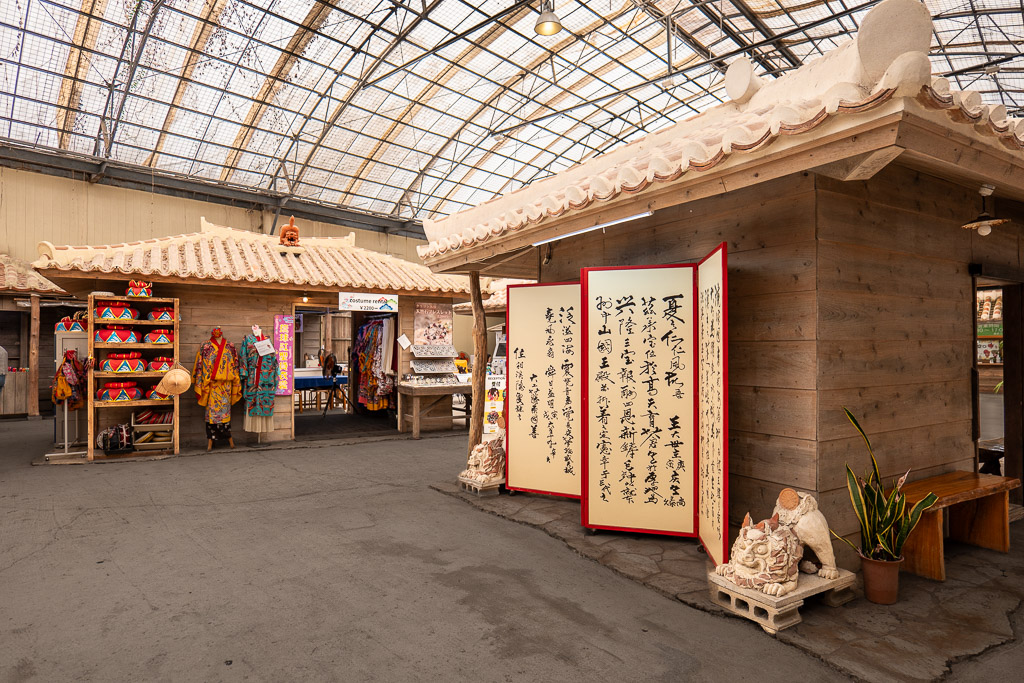 Ryuso dress-up corner with red and yellow Ryukyu royal court costumes and Sanshin folk-song calligraphy folding screen