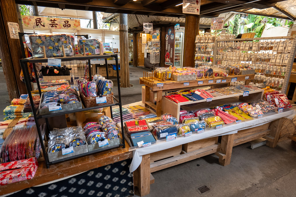 Ryukyu Village souvenir corner with Bingata-dyed goods, chopsticks, and other Okinawan crafts displayed in folk-art shop
