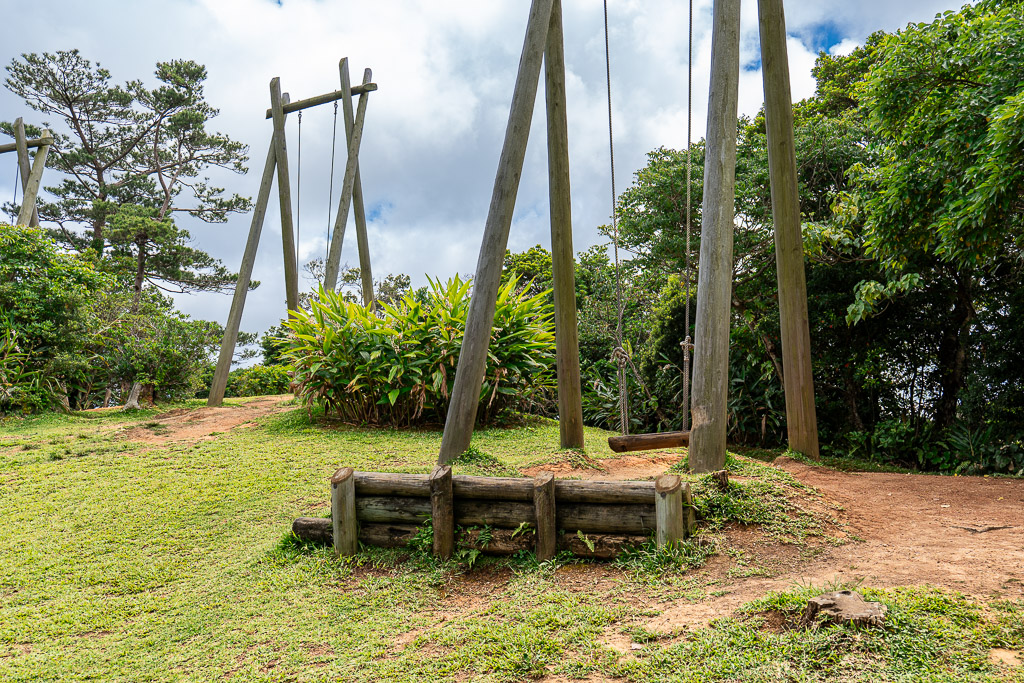 Wooden swing at Bios no Oka — tall log frame holding thick rope swings on a grassy hill
