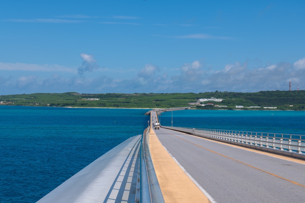 View from a car crossing Irabu Ohashi Bridge with open road and turquoise sea on both sides