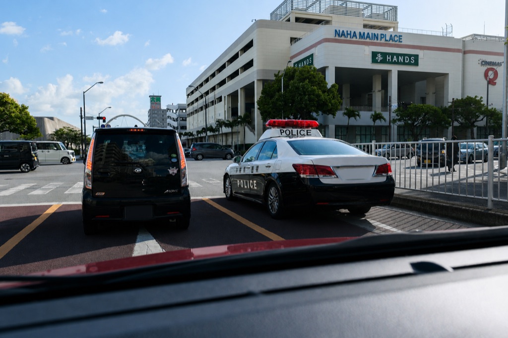 Japanese police car next to a rental car at a Naha intersection showing strict enforcement