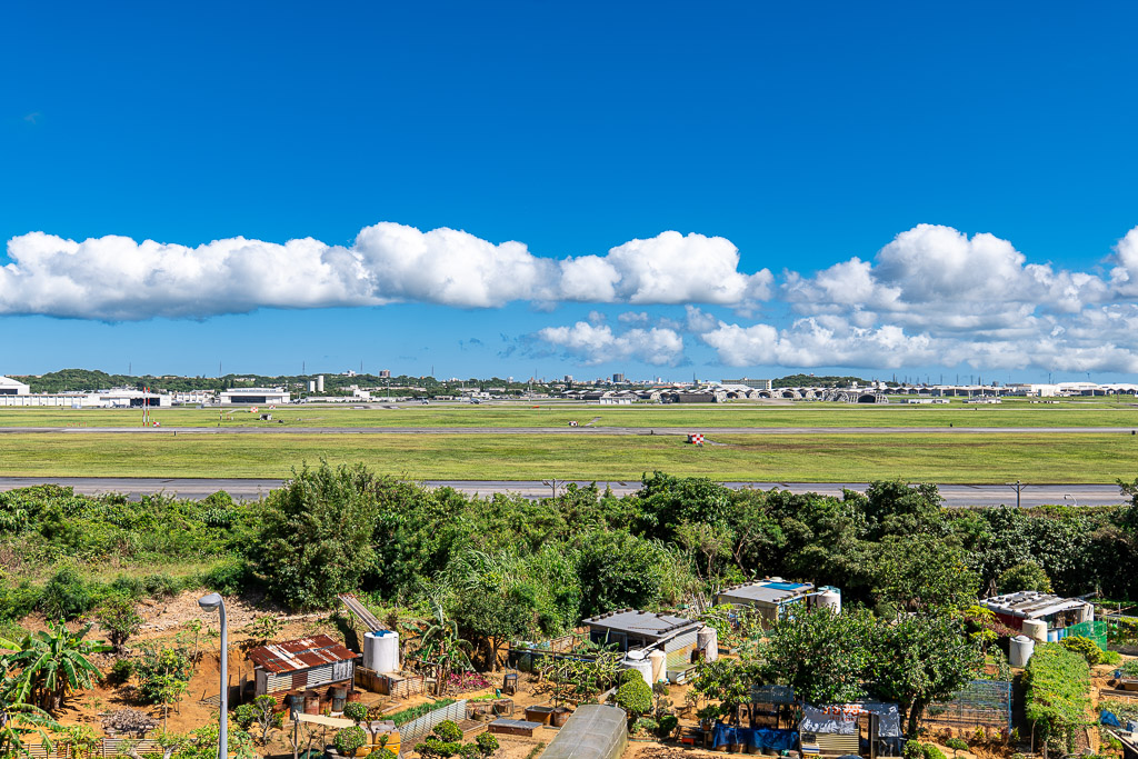 Wide runway at Kadena Air Base stretching to the horizon under blue sky and clouds
