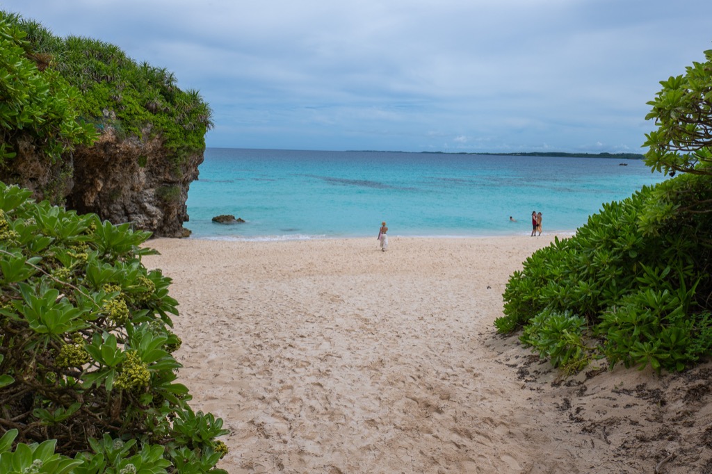 Final descent to Sunayama Beach with visitors on white sand and turquoise water beyond