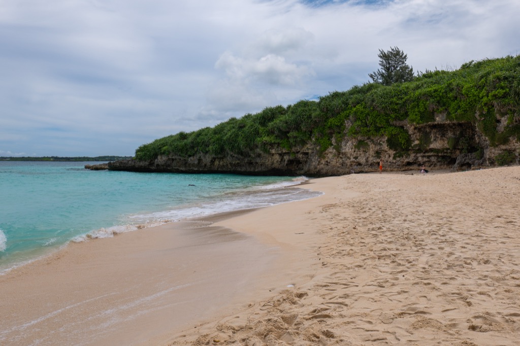Wide panorama of Sunayama Beach with white sand uplifted coral cliffs and turquoise Miyako Blue water