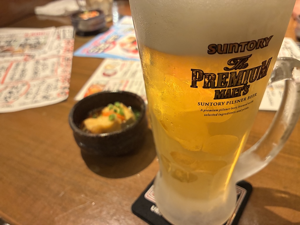 Frosted glass of Suntory Premium Malt's draft beer and a small otoshi side dish at Umi no Chinbora