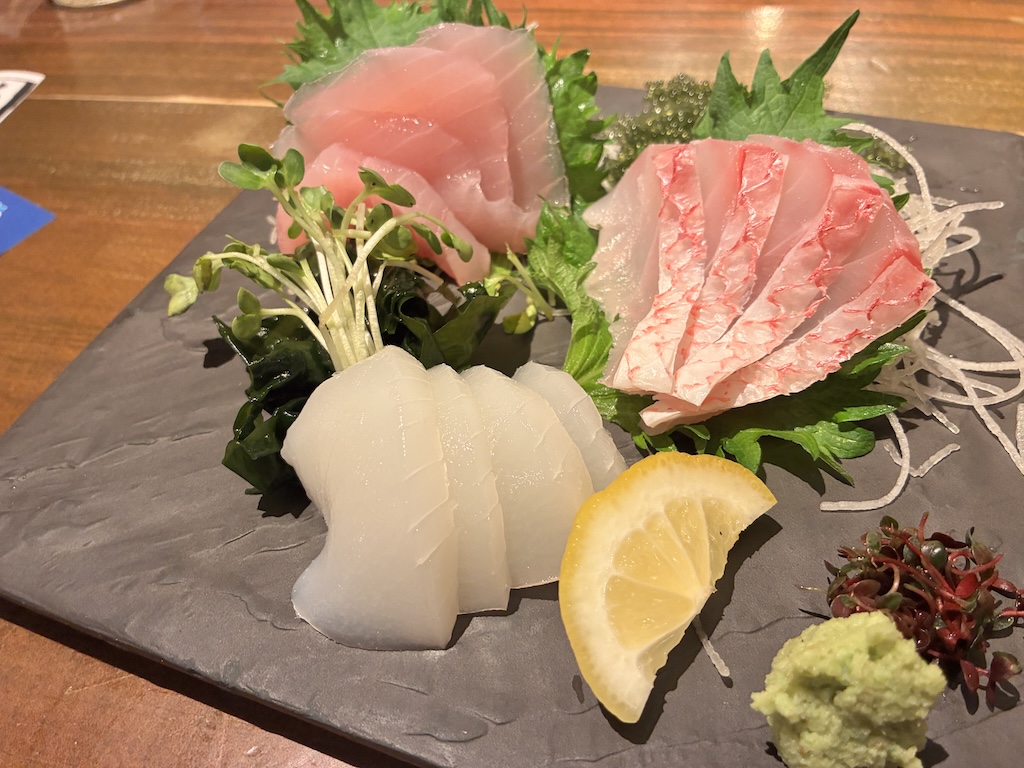 Sashimi assortment at Umi no Chinbora — tuna, sea bream, squid on a black slate plate