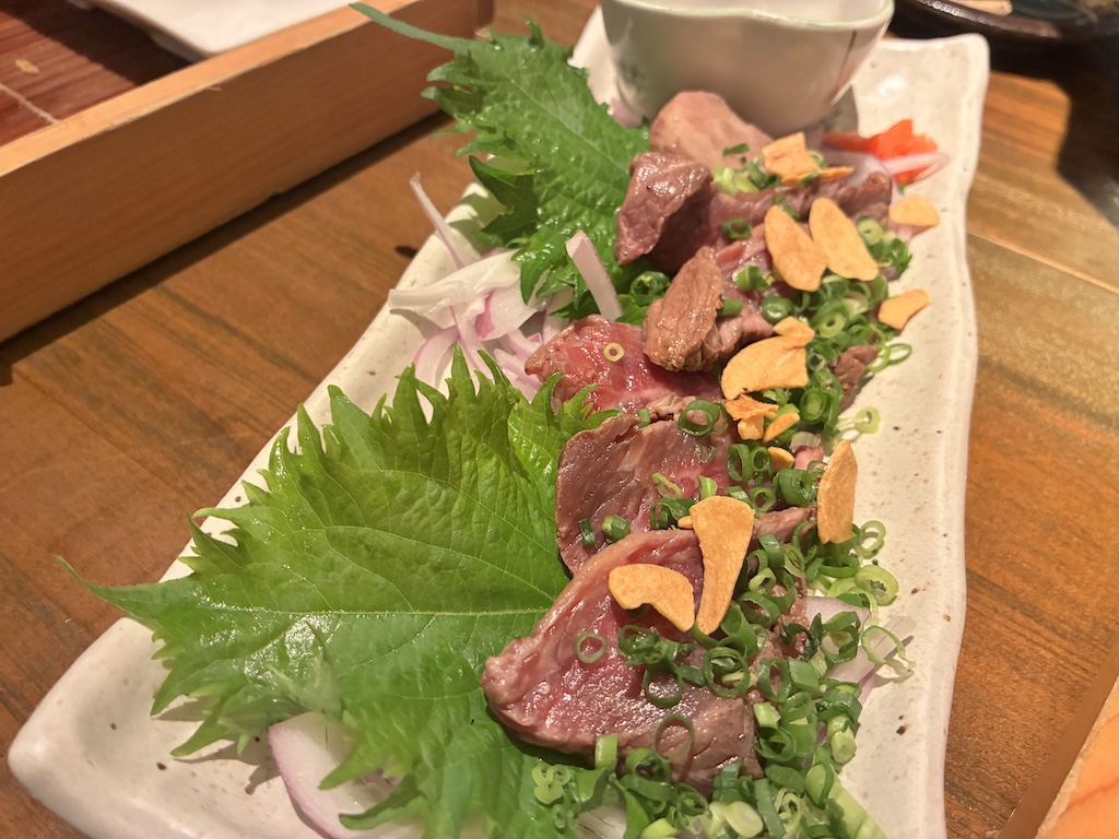 Beef tataki — lightly seared beef slices with garlic chips and green onion at Umi no Chinbora