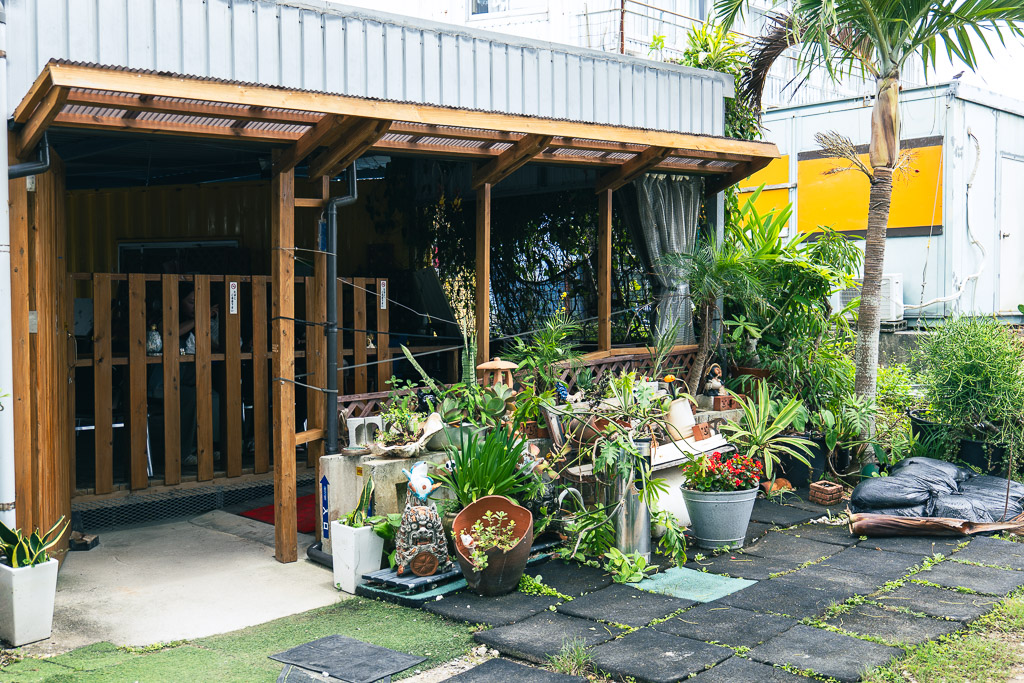 Small covered seating beside Oshiro Tempura — wooden benches with potted plants