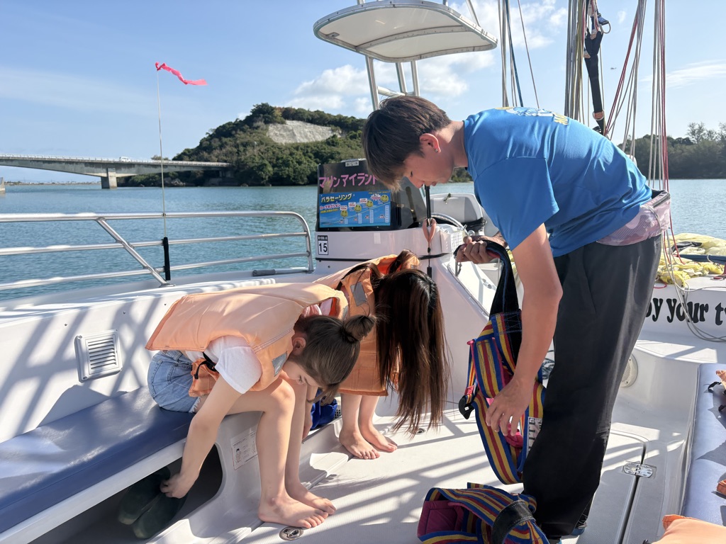 Okinawa parasailing instructor helps a participant fit a life jacket and harness on the boat