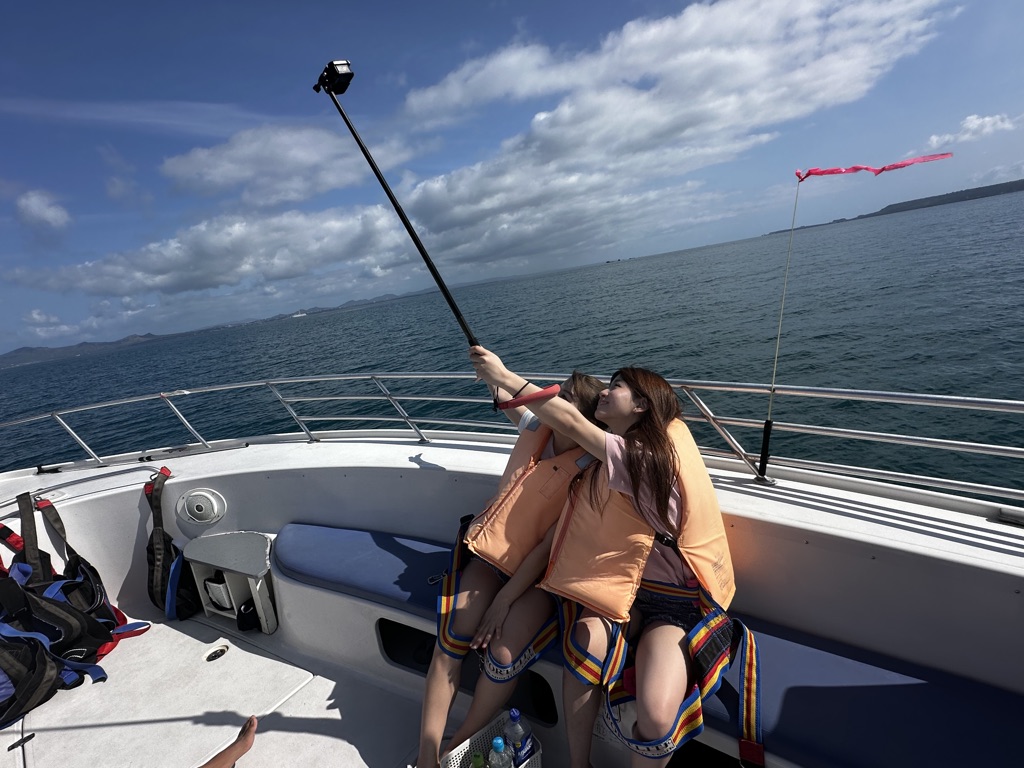 Two travelers take a selfie on the Okinawa parasailing boat with ocean view