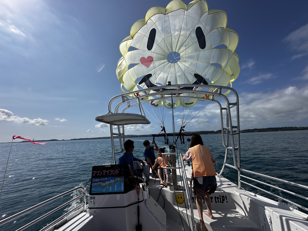 Yellow smiley-face parasailing parachute unfurls behind the boat in central Okinawa
