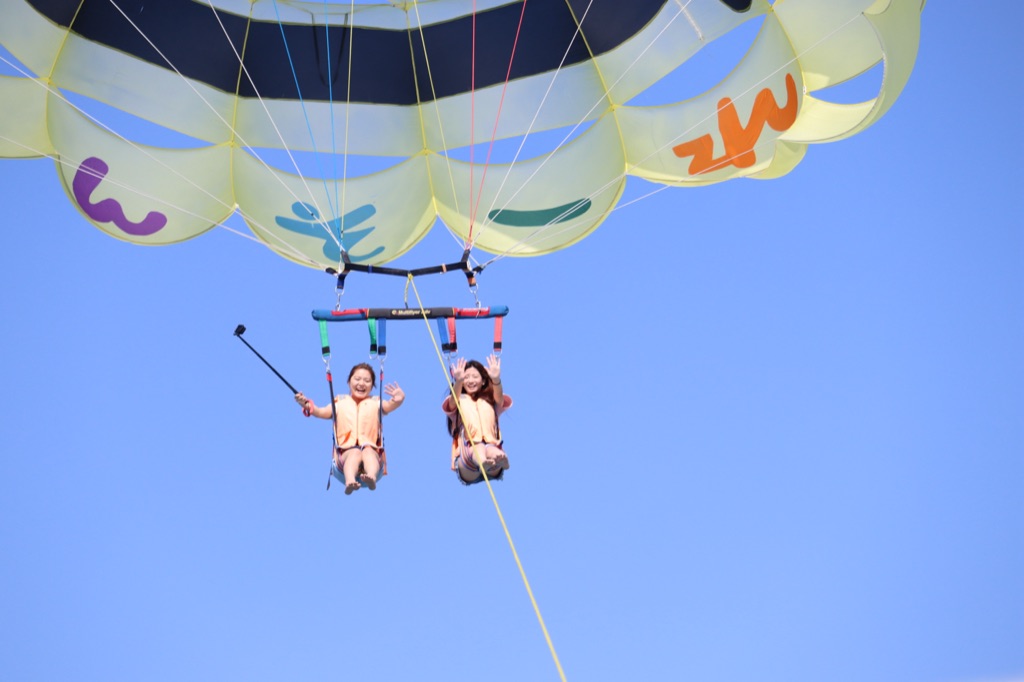 Close-up of two parasailers in the air under the smiley parachute over Okinawa