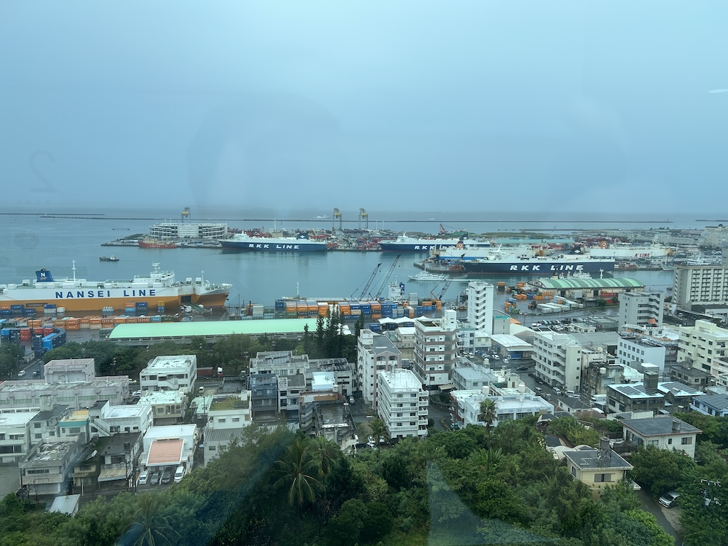Naha Port in Okinawa under a gray pre-typhoon sky with RKK Line and Nansei Line ferries docked — typical scene before an Okinawa typhoon hits in summer