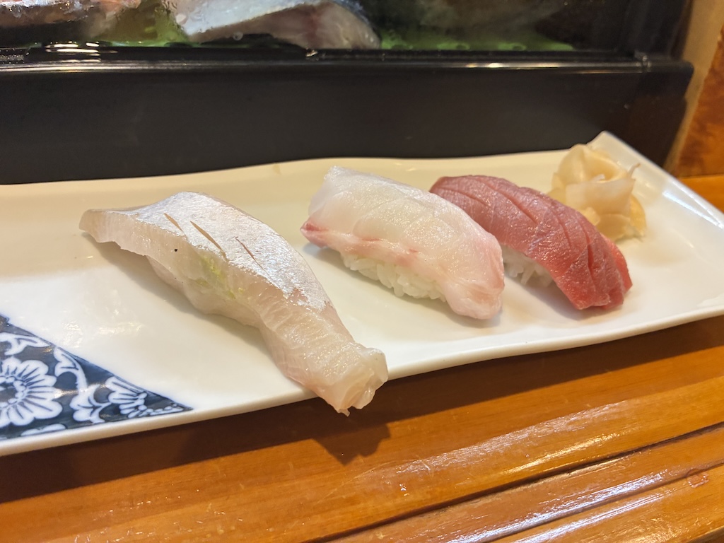 A simple plate of three nigiri pieces — white-flesh fish, sea bream, and lean tuna — at an Osaka sushi bar
