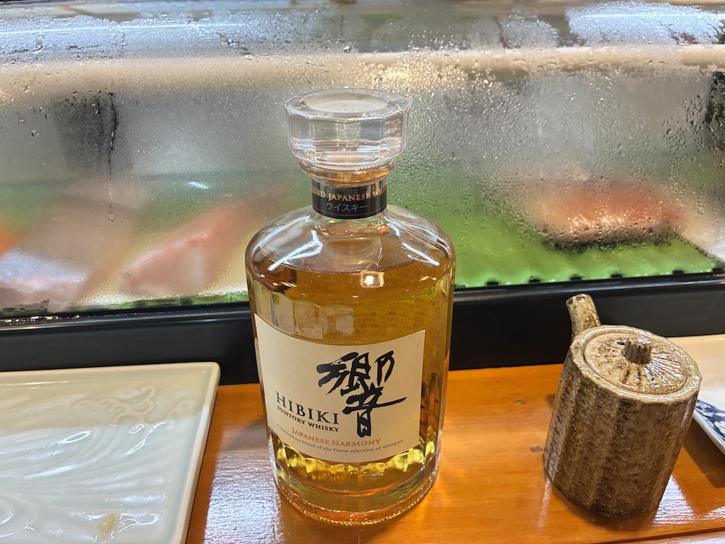 A bottle of Hibiki Japanese Harmony whisky on a sushi counter — premium Japanese whisky popular at high-end restaurants