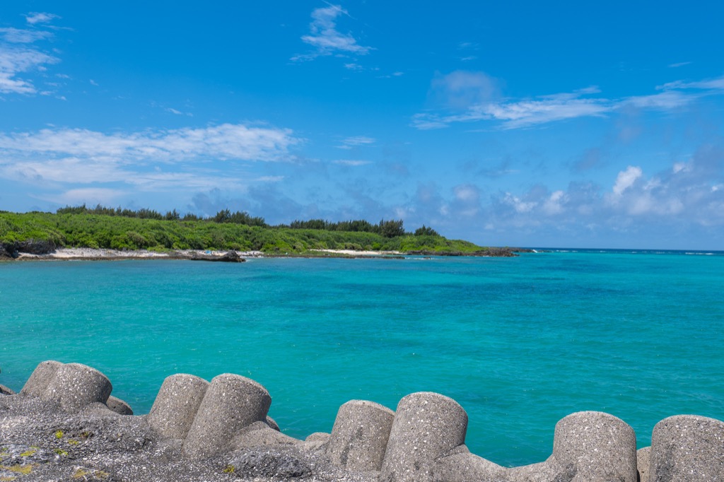 Small turquoise cove with tetrapods and a green island shoreline near 17END