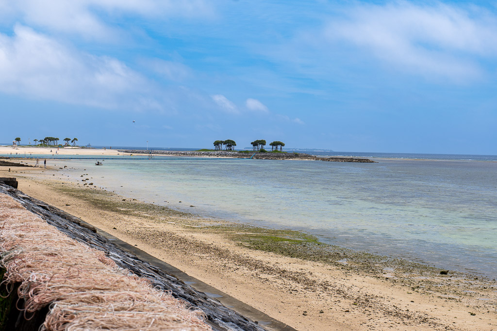 Shallow Bise beach at low tide with the small islet of Bise-zaki and Ie Island in the distance
