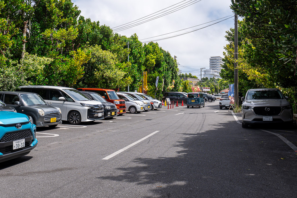 Small private parking lot near the entrance of Bise Fukugi Tree Road with rental cars parked in a row