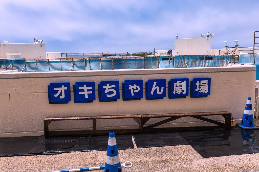 Blue Okichan Theater sign at the dolphin show pool in Ocean Expo Park