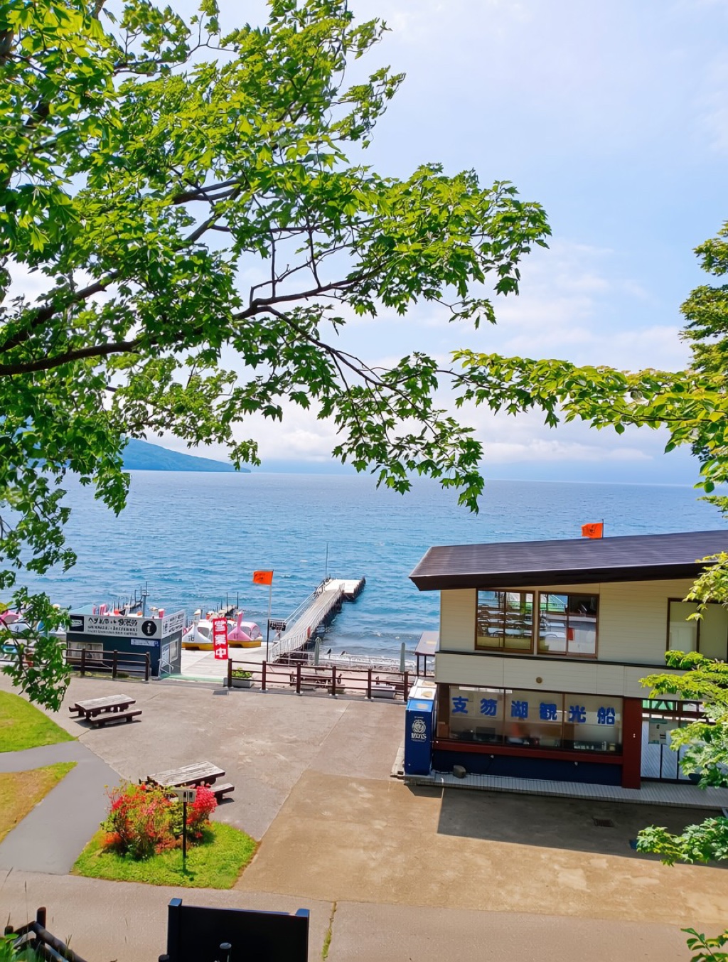 Hokkaido weather in June at Lake Shikotsu in June — a traveller paddles on a paddleboard over crystal-clear caldera water