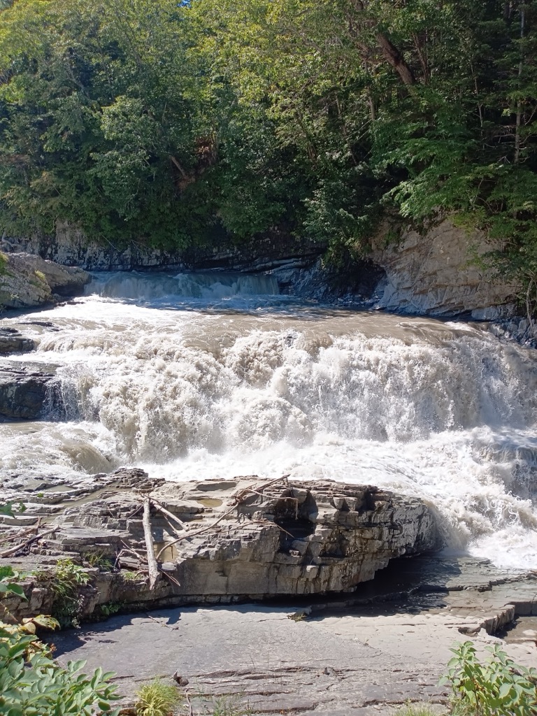 Sandan Falls in Ashibetsu, Hokkaido — three-step waterfall in a rocky green ravine during September weather