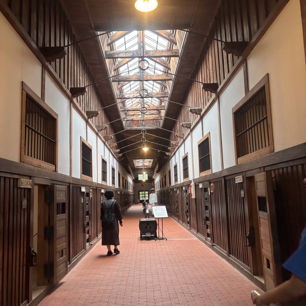 Interior hallway of the historic Abashiri Prison Museum with wooden cell doors and skylight