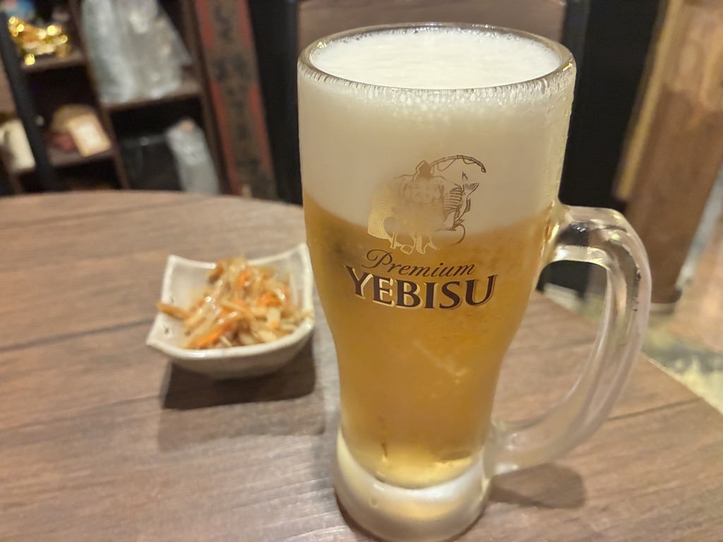 Frosty mug of Yebisu premium beer at a Japanese izakaya table — cozy dining scene