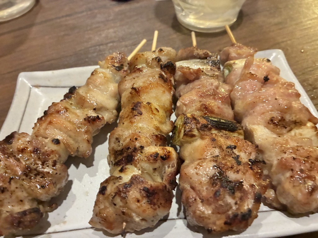 Yakitori grilled chicken skewers on a white plate at a Japanese izakaya