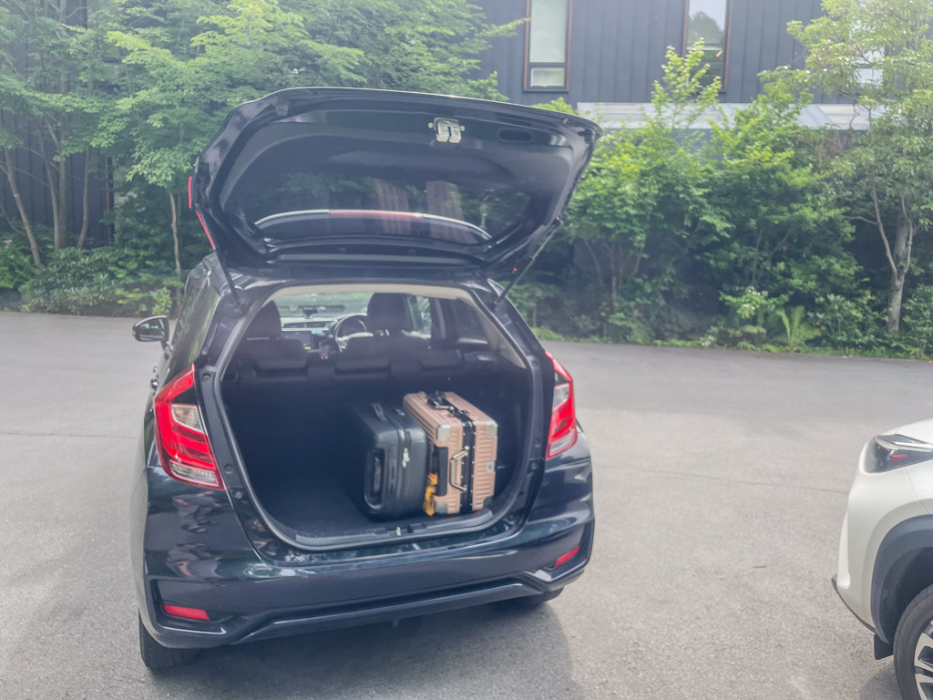 Honda FIT tailgate open at the accommodation with two suitcases loaded