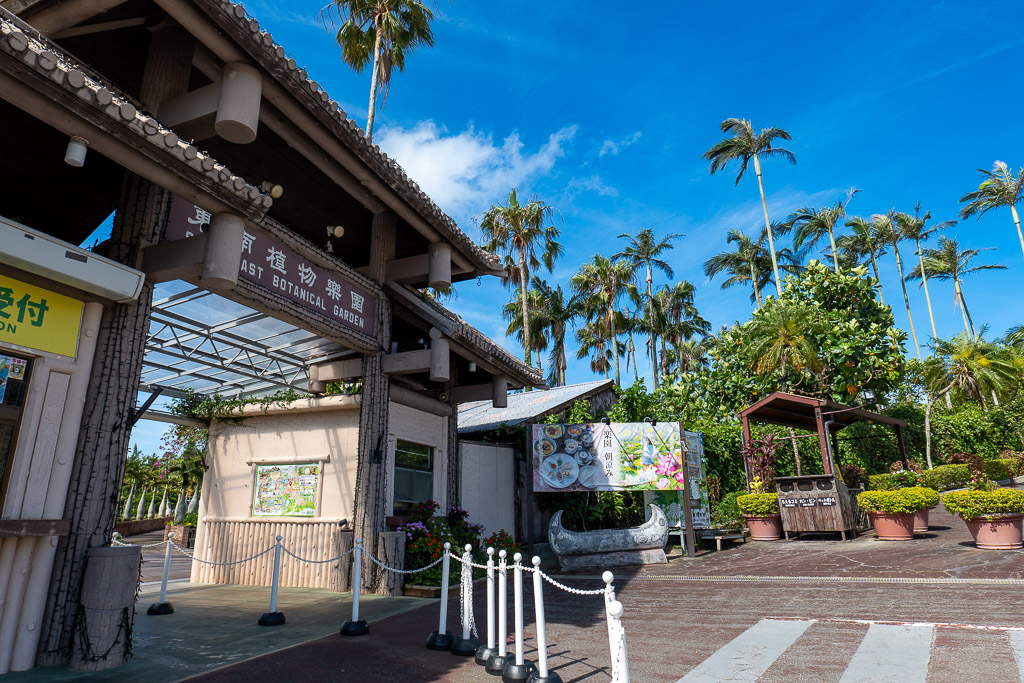 Entrance gate and reception building of Southeast Botanical Gardens framed by palm trees