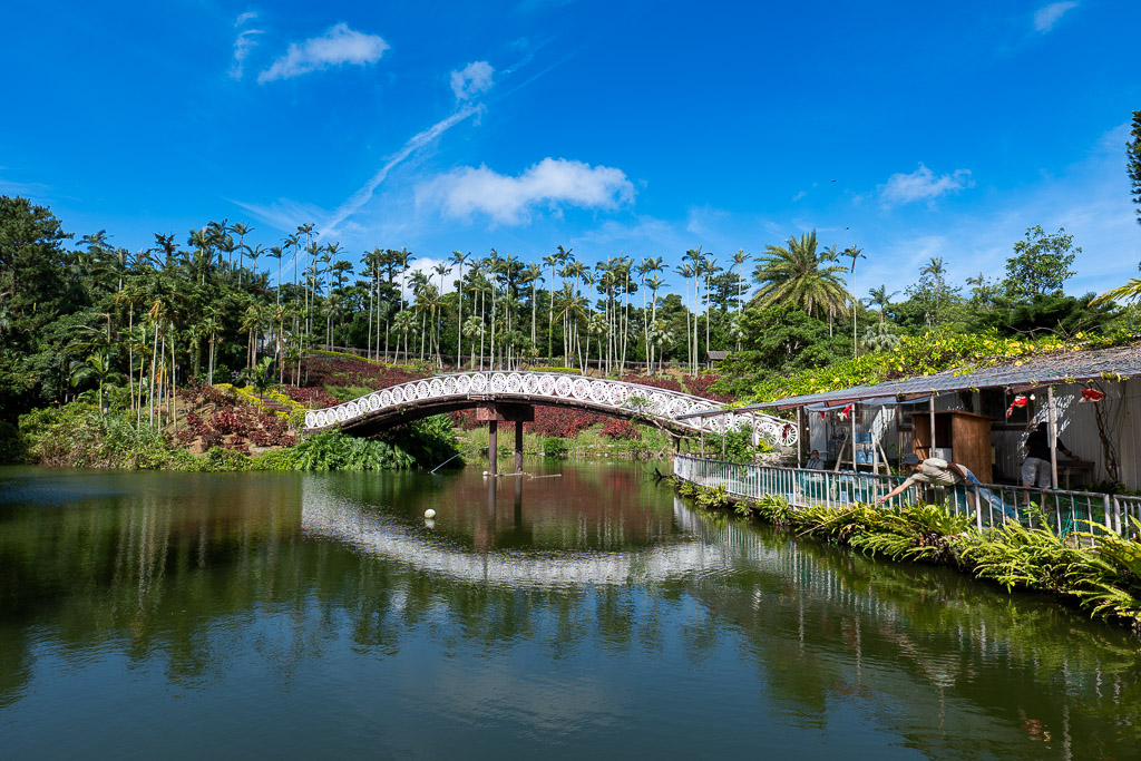 White arch bridge reflected in a calm lake at Southeast Botanical Gardens Okinawa