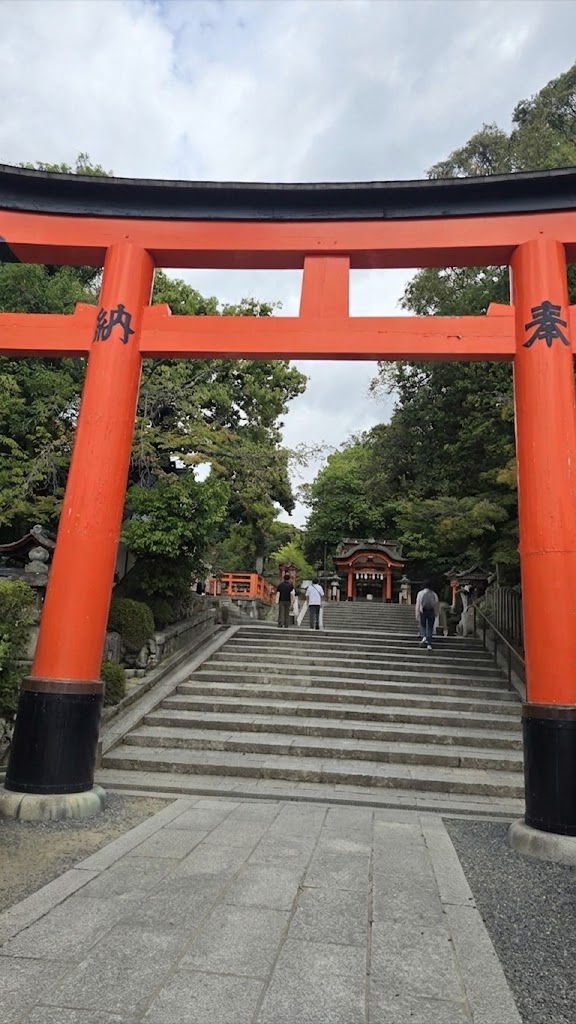 Fushimi Inari Taisha visitors walking up the crowded main torii gate approach with steps and green trees Kyoto