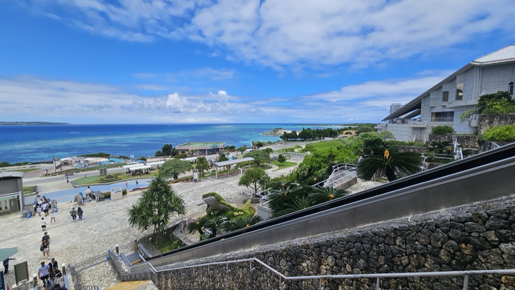 Panoramic view of Ocean Expo Park lawns and blue sea from the escalator descending to Churaumi Aquarium