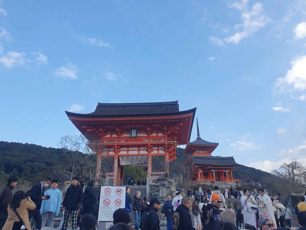 Bundled-up winter visitors in front of Kiyomizu-dera Nio-mon gate in January light